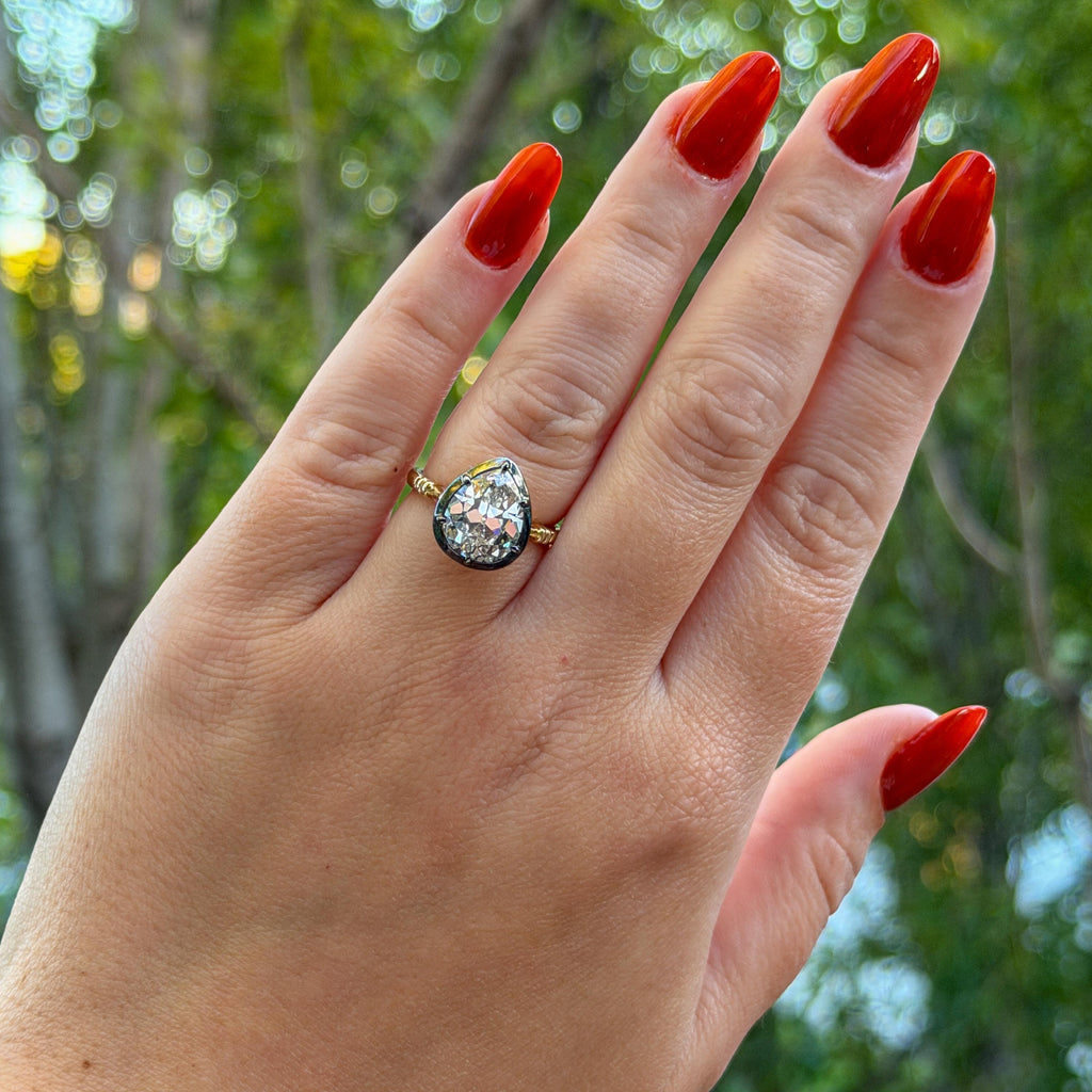 The Caroline ring: antique pear cut lab-grown diamond in a blackened collet on a yellow gold shank