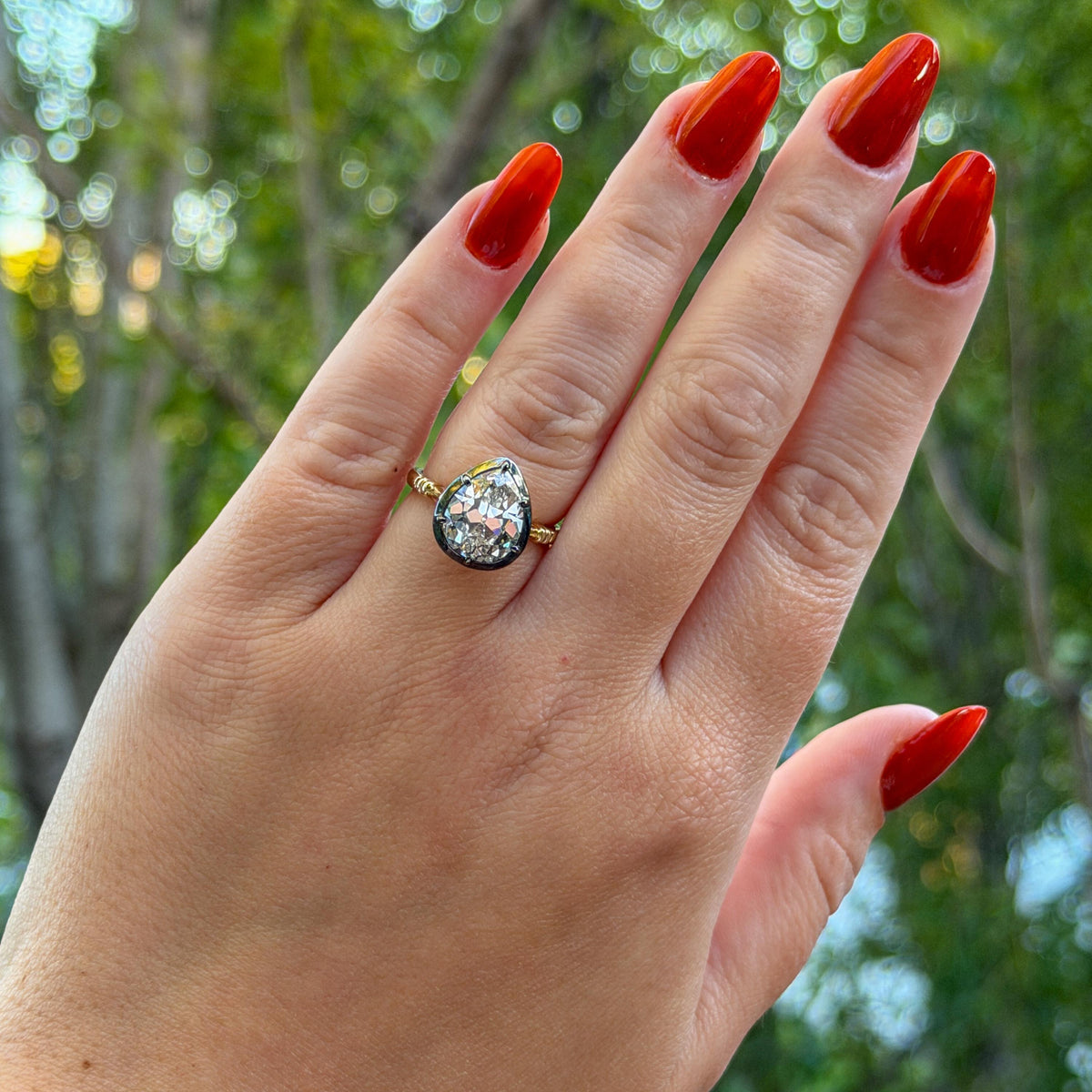 The Caroline ring: antique pear cut lab-grown diamond in a blackened collet on a yellow gold shank