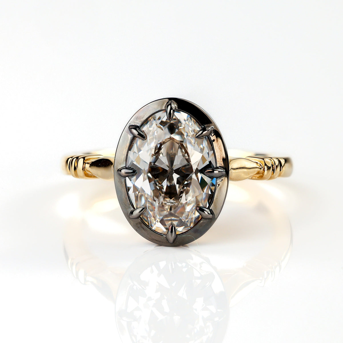 The Caroline ring: antique oval lab-grown diamond in a blackened collet on a yellow gold snake shank